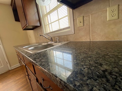 A kitchen with a granite countertop and a window.