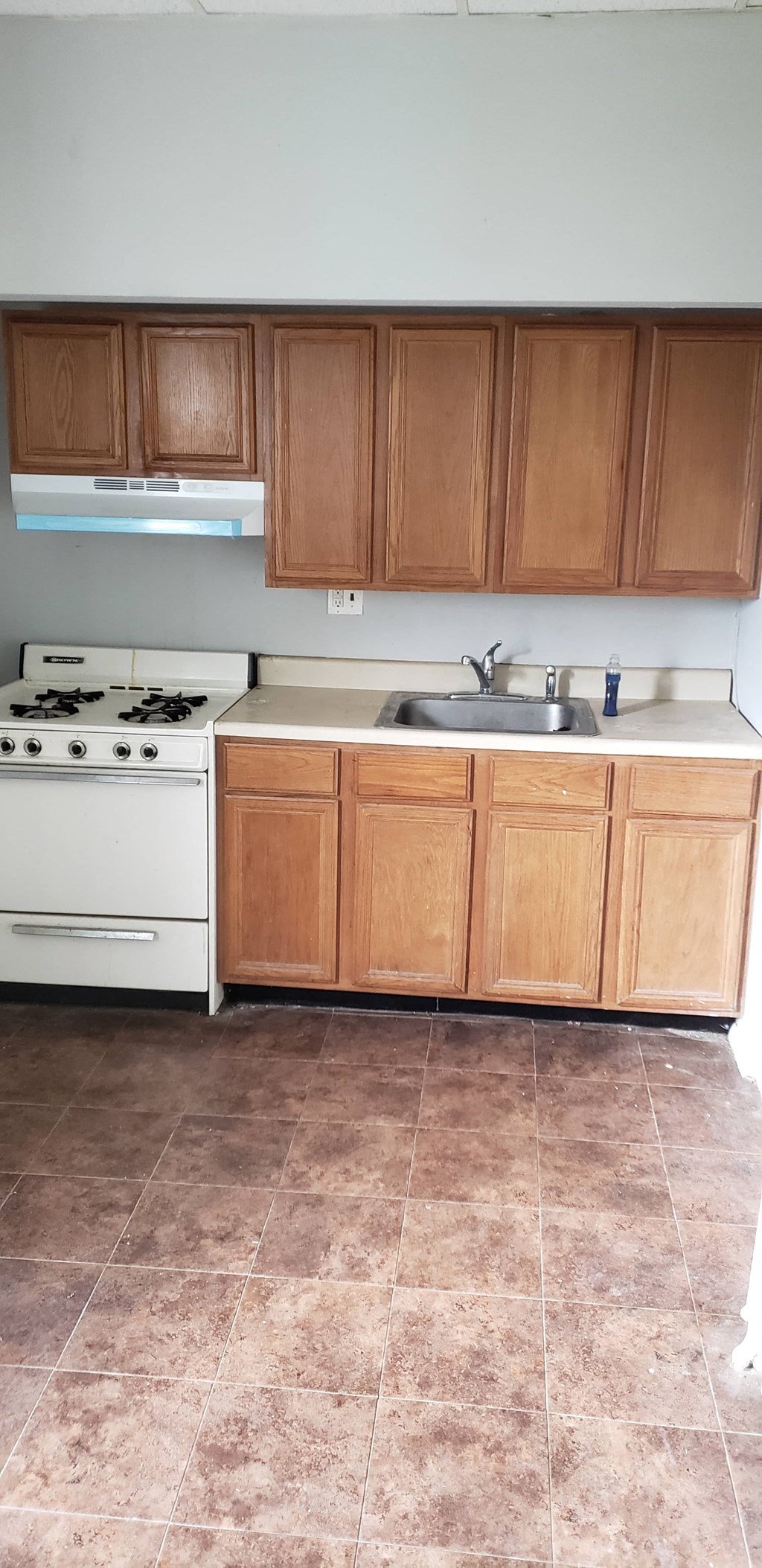 a kitchen with a stove and a sink and wooden cabinets