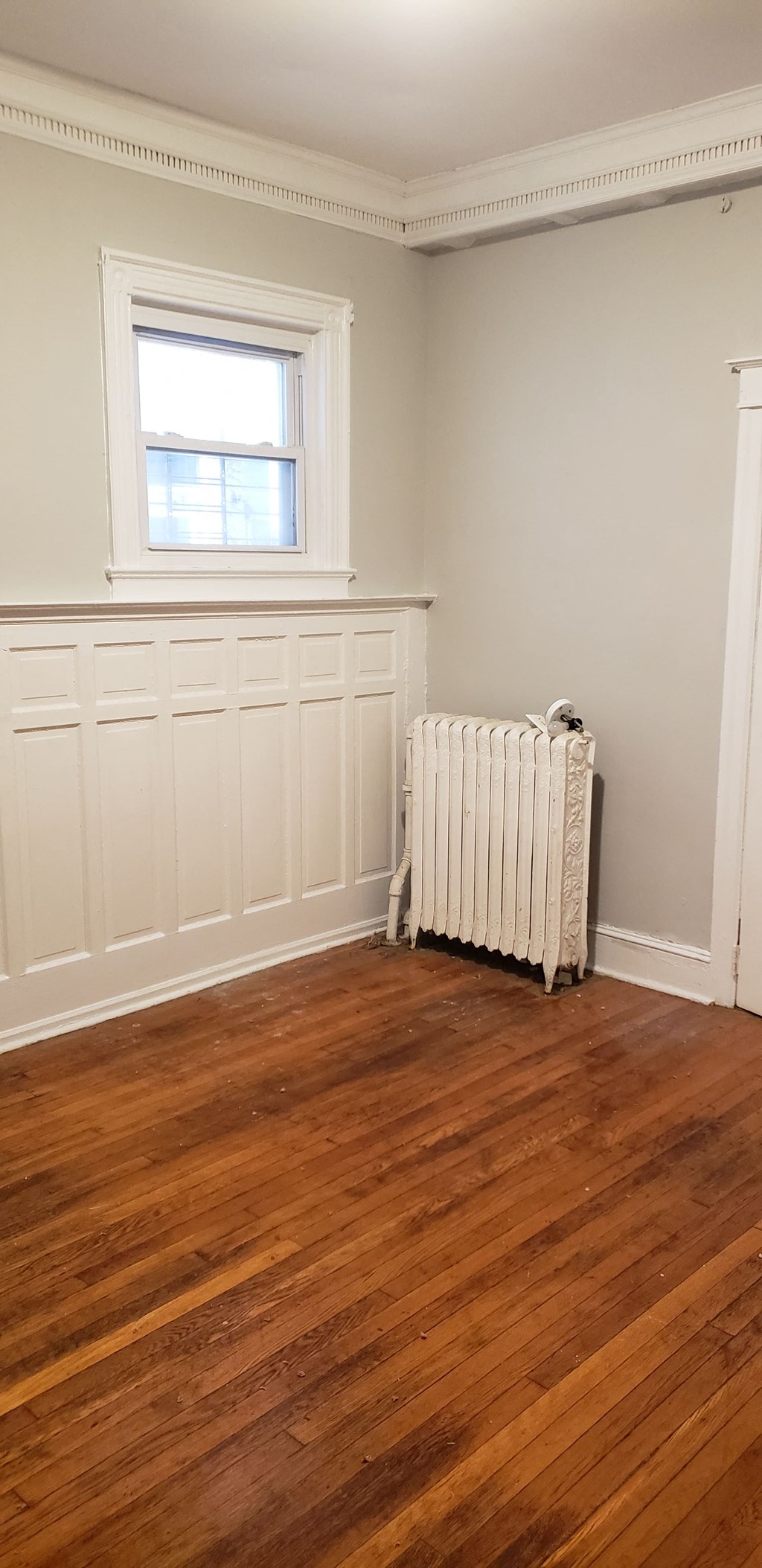 a room with wooden floors and a radiator and a window