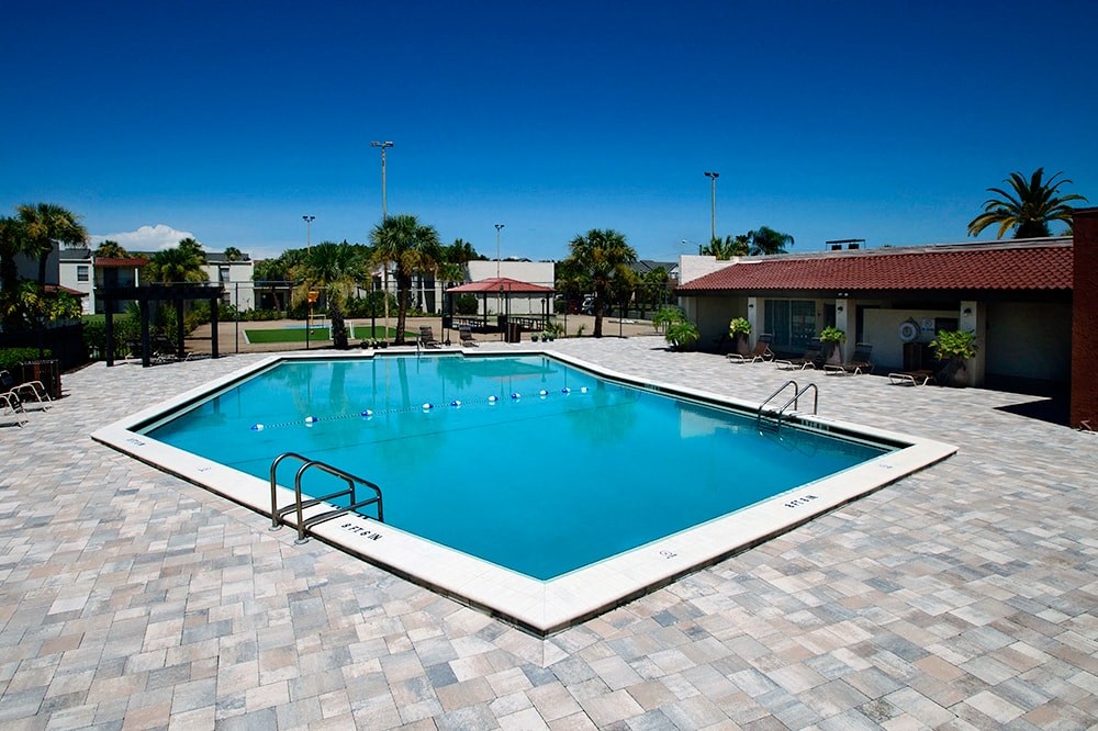 a large swimming pool with a house in the background
