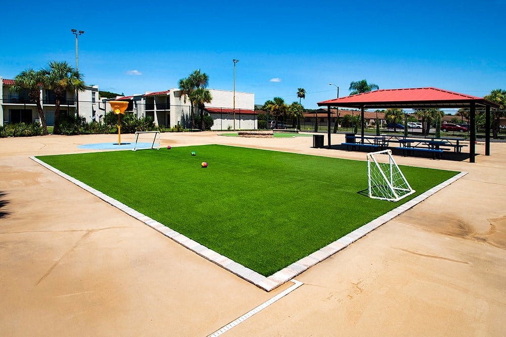 an artificial turf field in a park with a swing set