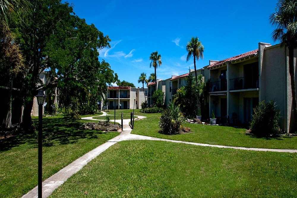 a walkway between two apartment buildings with palm trees