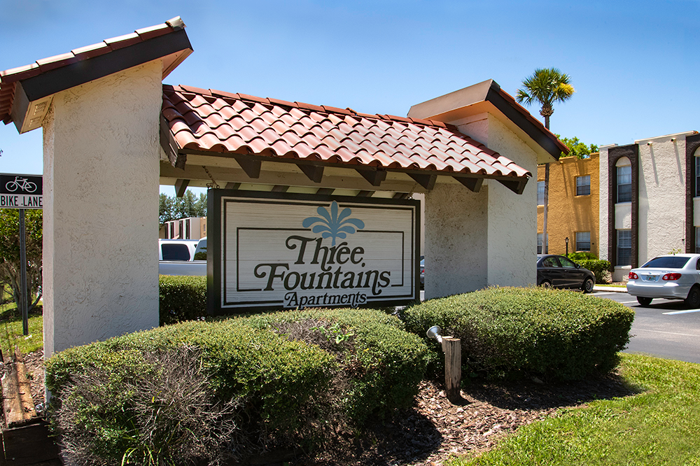 a sign for three fountain apartments in front of a building