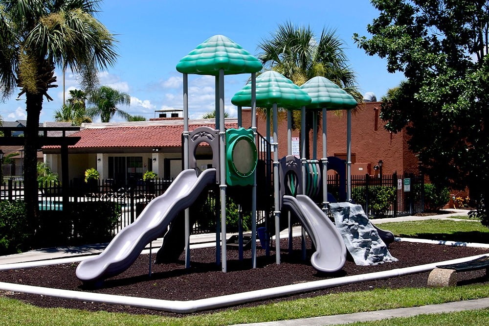 a playground with three slides and two umbrellas