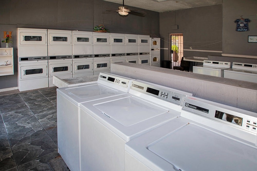 a group of white washers and dryers in a laundry room