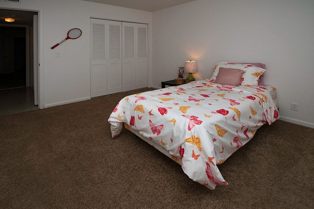 a bedroom with a bed with a white comforter