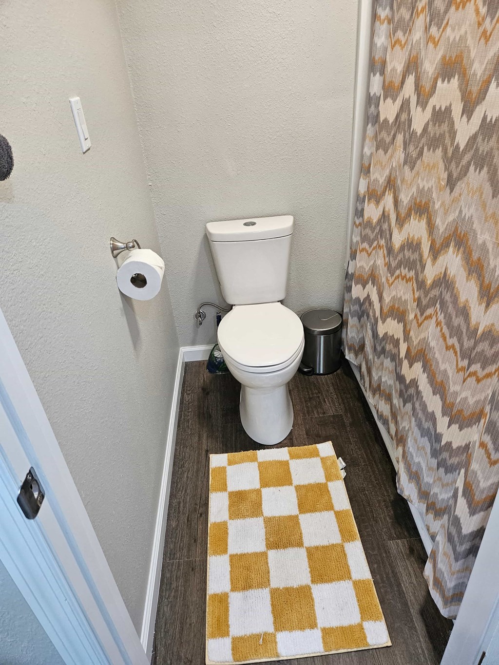 a bathroom with a toilet and a checkered shower curtain