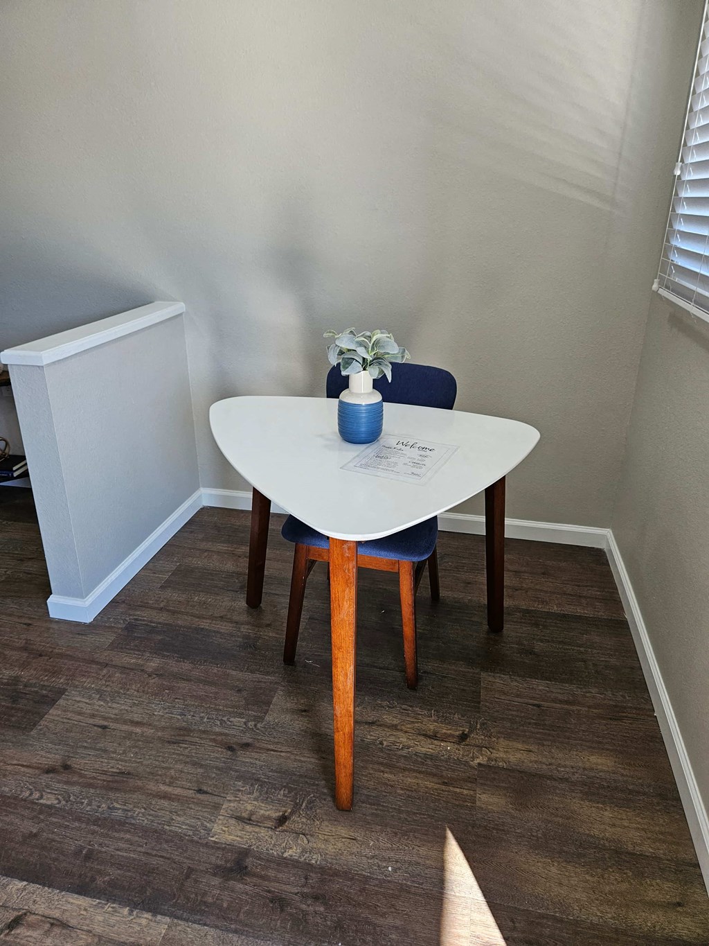 a small dining room with a white table and a blue chair