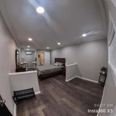 a bedroom with a bed in a room with white walls and wood floors