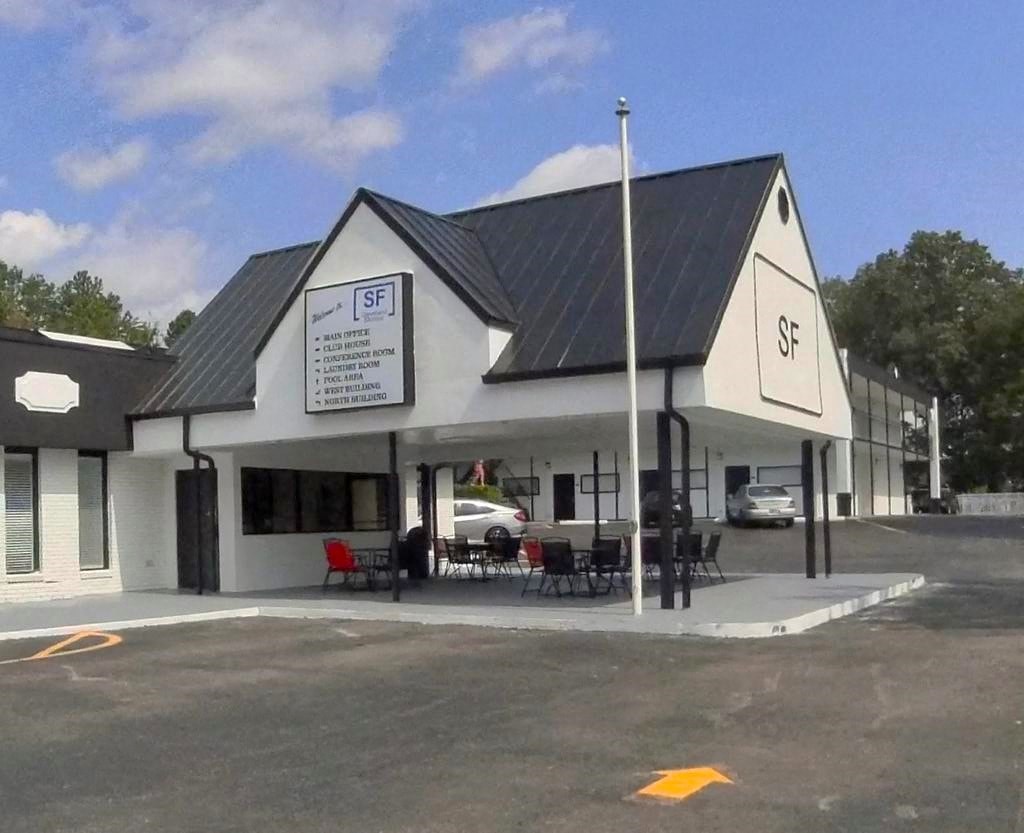 a white building with tables and chairs outside and a parking lot