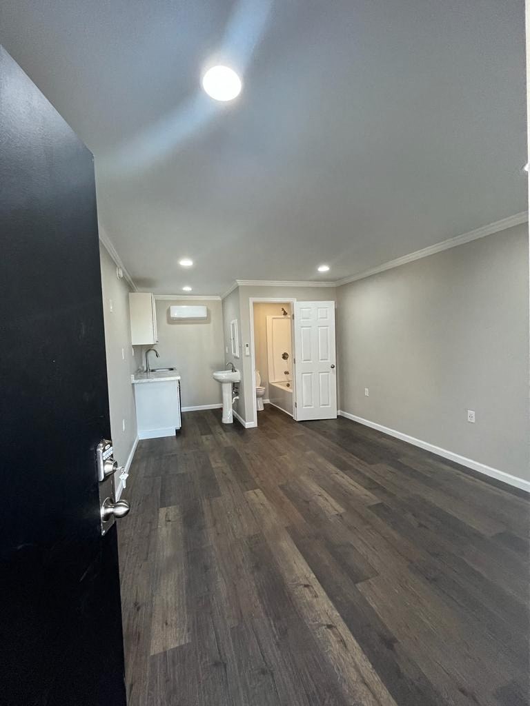 a living room with wood floors and a white bathroom