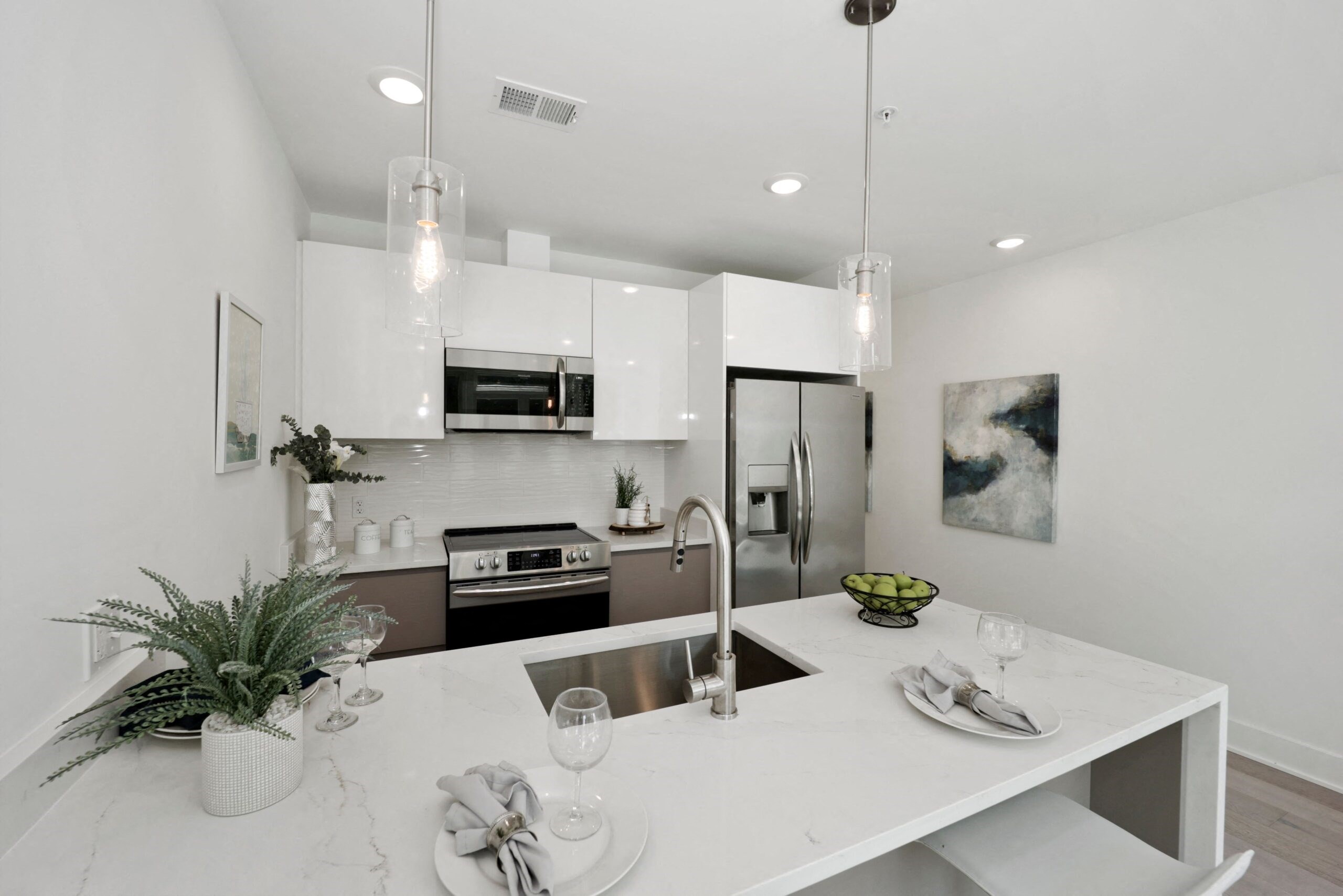 a white kitchen with white counter tops and stainless steel appliances