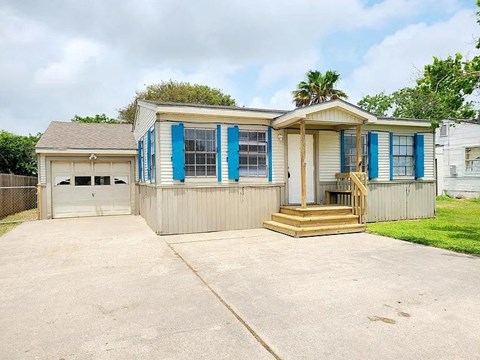 a small house with blue shutters and a driveway