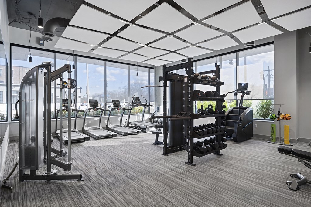 a gym with treadmills and weights in a building with large windows