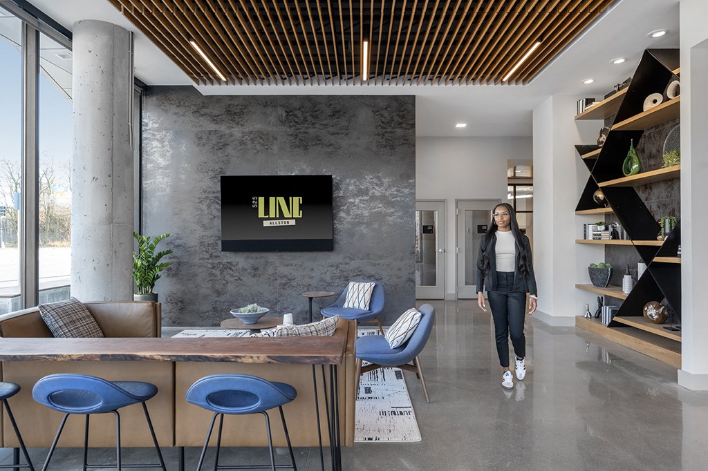 a woman walks through a lobby with a table and chairs