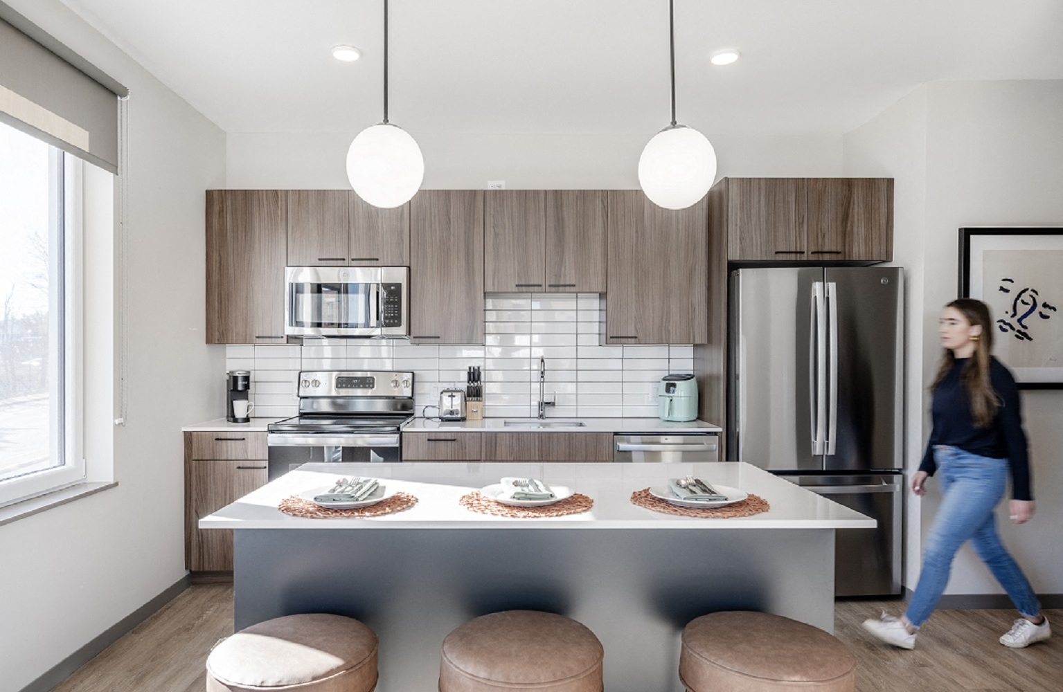 a kitchen with a island and a woman walking