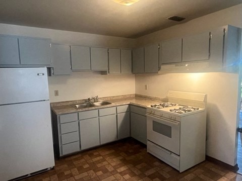 A kitchen with a white fridge, white stove, and white cabinets.