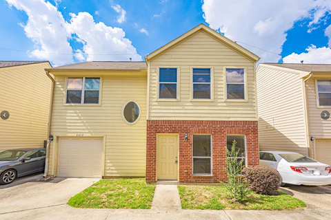 A house with a red brick front door and a garage.