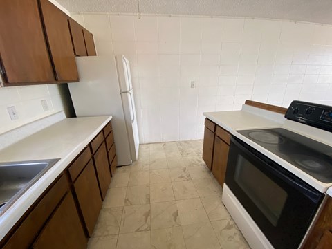 A kitchen with brown cabinets and a white fridge.