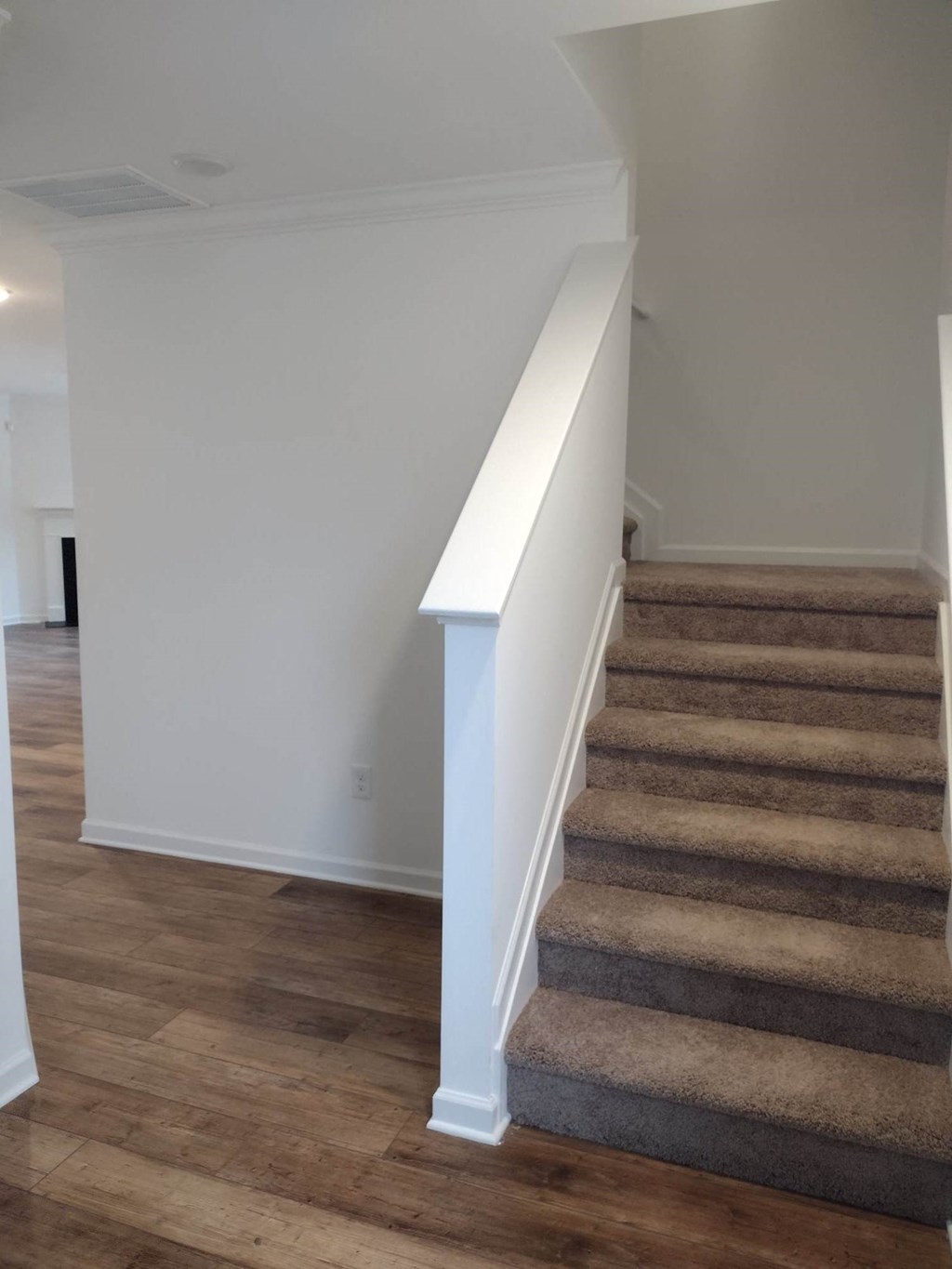a stairway with carpeted stairs leading up to a white wall with a railing