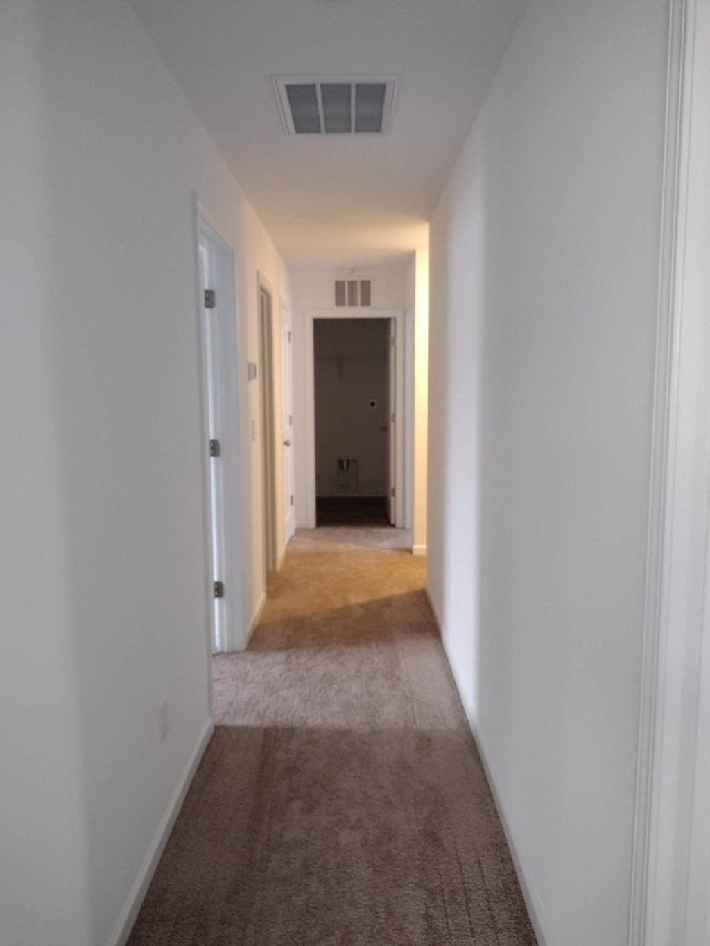 a long hallway with white walls and carpeting and a white ceiling with a white