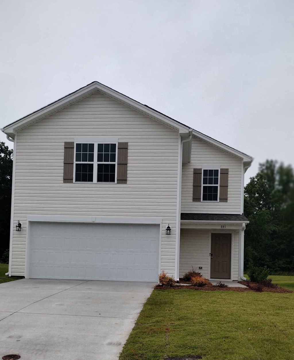 a white house with a garage door and a driveway
