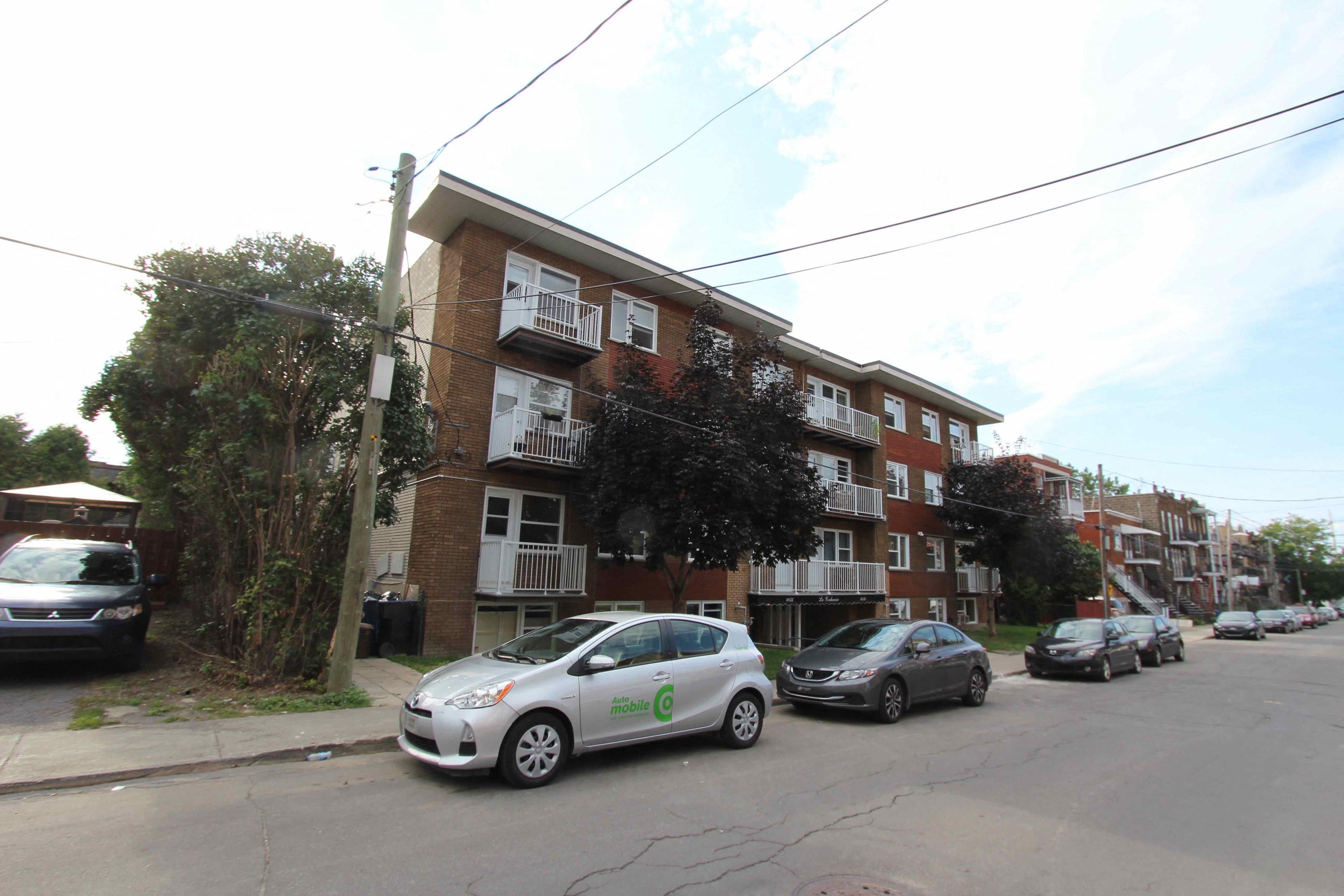 a city street with cars parked in front of an apartment building
