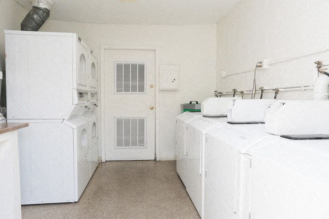 a white laundry room with two white machines and a white door