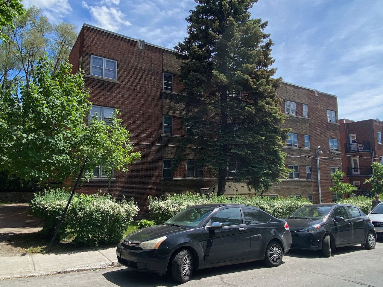 the apartment building has three cars parked in front of it