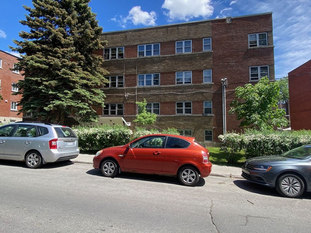a red car parked in front of a brick building