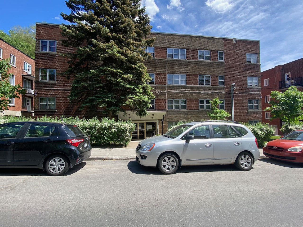 a parking lot in front of a brick building with cars parked in front