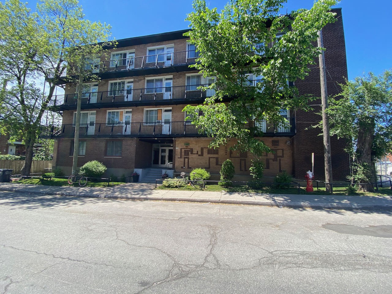 an apartment building with a street and trees in front of it
