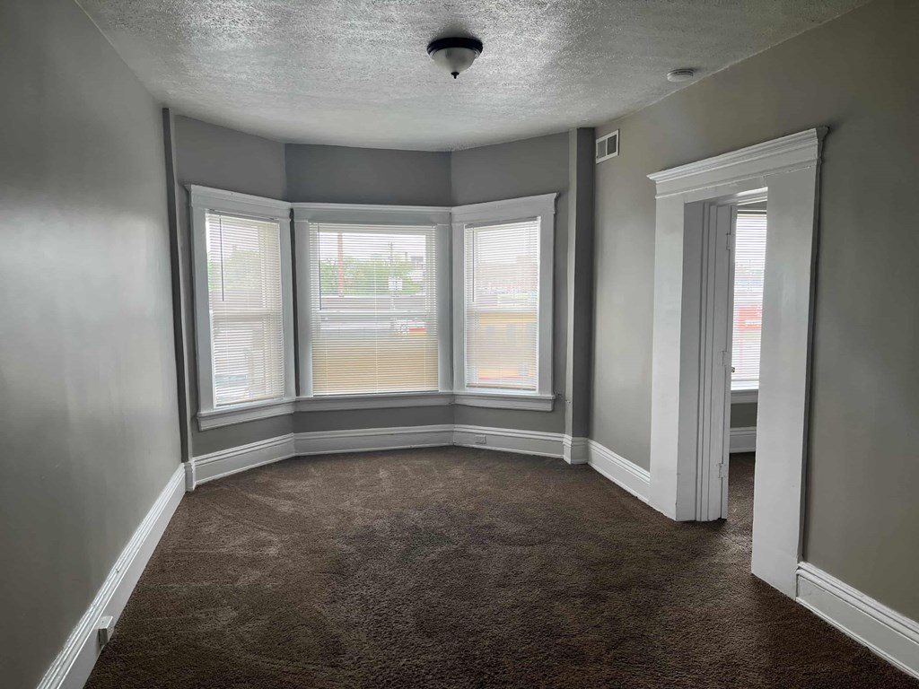 an empty room with three windows and a carpet