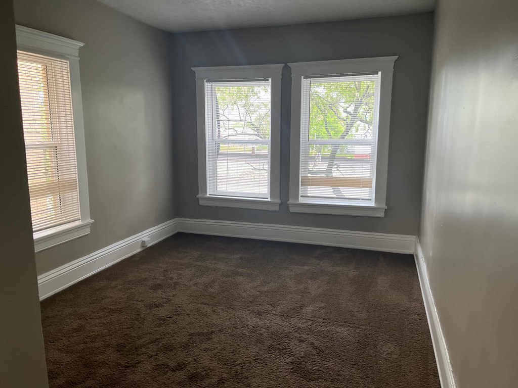 a empty room with three windows and a carpet