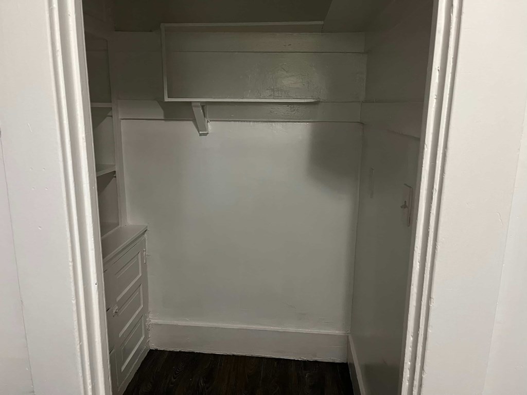 a small closet with a white wall and a white