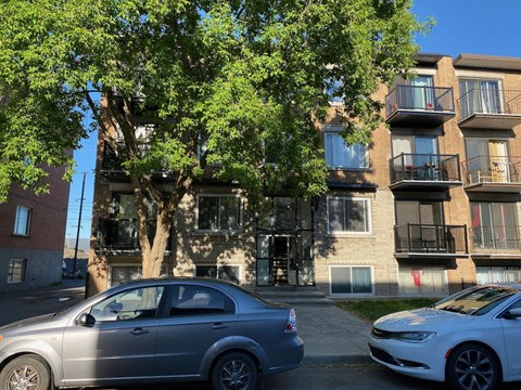 an apartment building with two cars parked in front of it