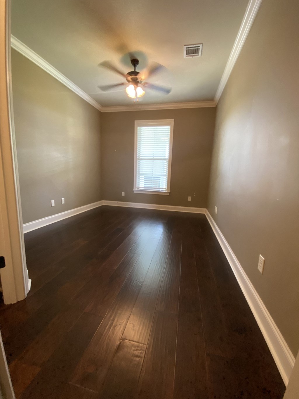 a empty room with wooden floors and a ceiling fan