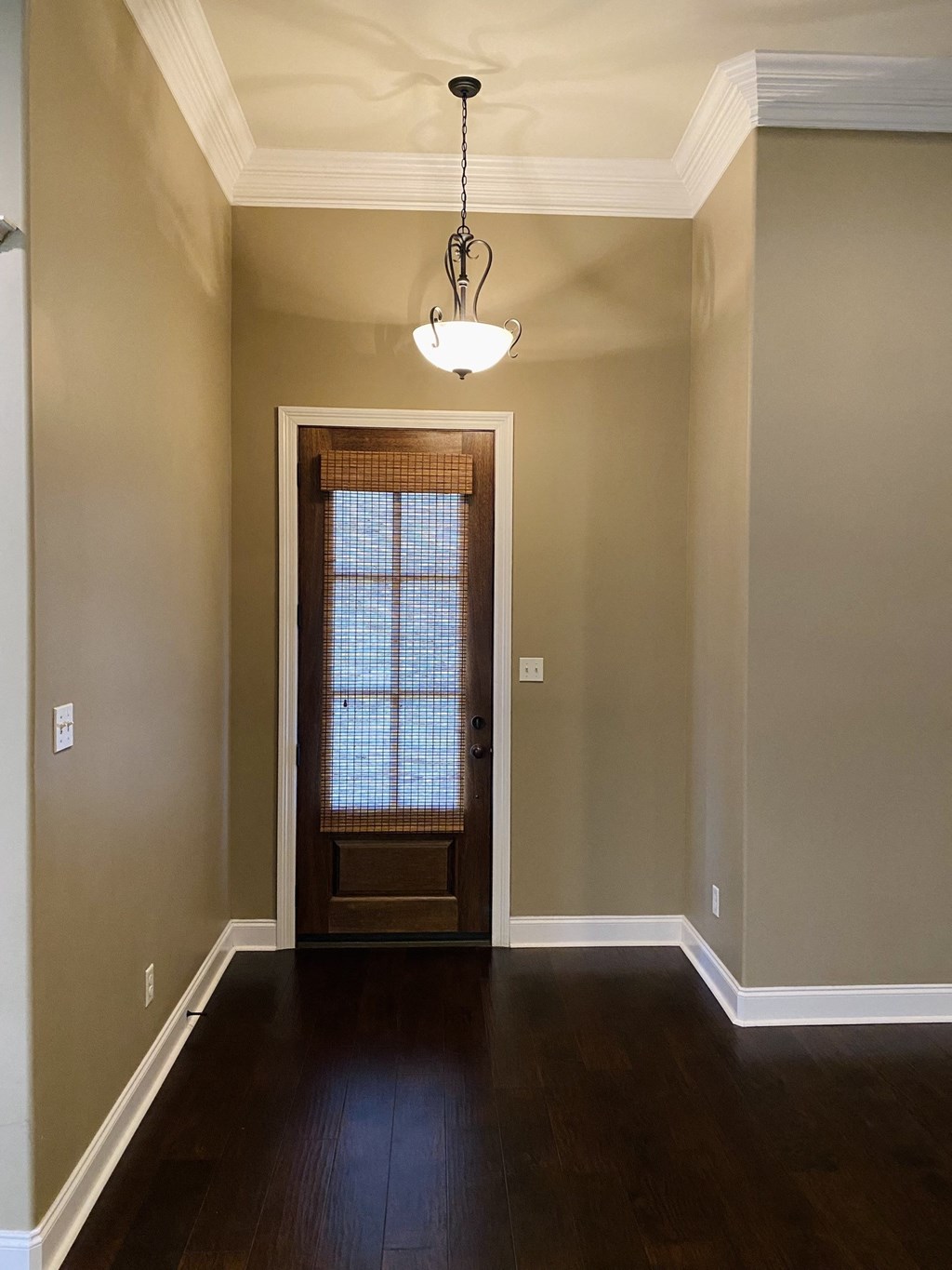 an empty living room with a wooden door and a chandelier