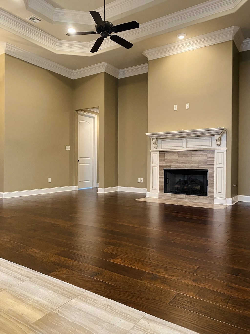 an empty living room with a fireplace and wooden floors