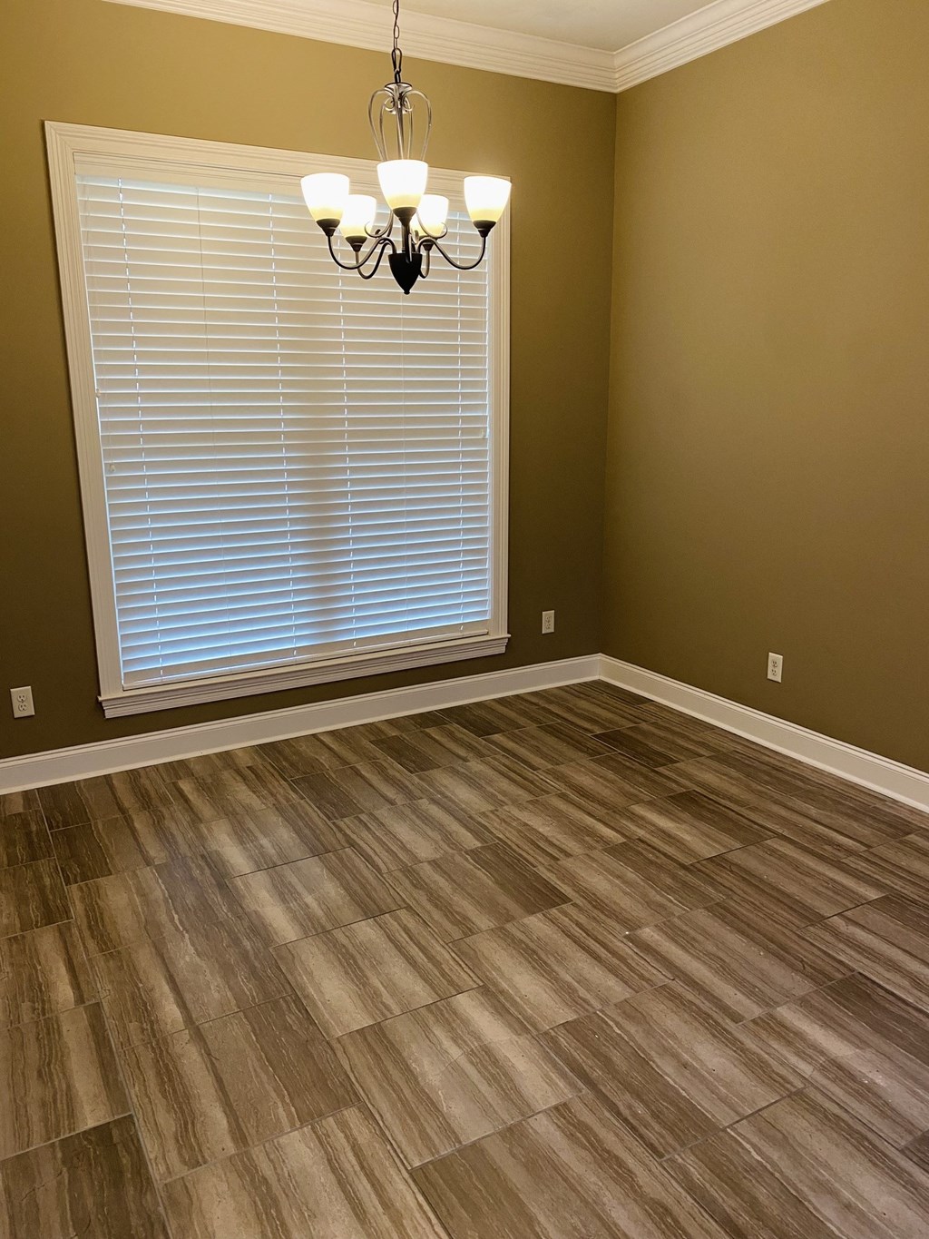 a living room with wood floors and a large window and a chandelier