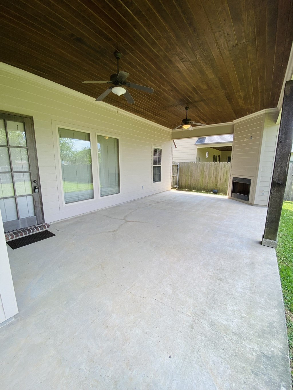 a covered patio with a wood ceiling and ceiling fans