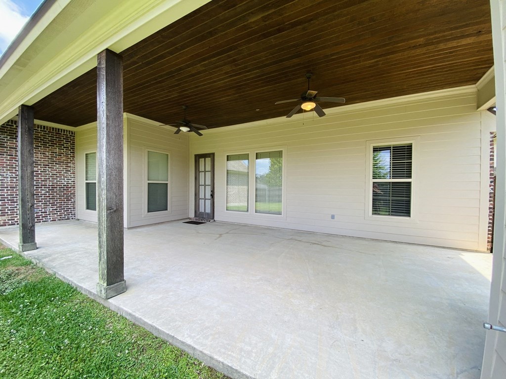 a covered patio with a ceiling fan and a door