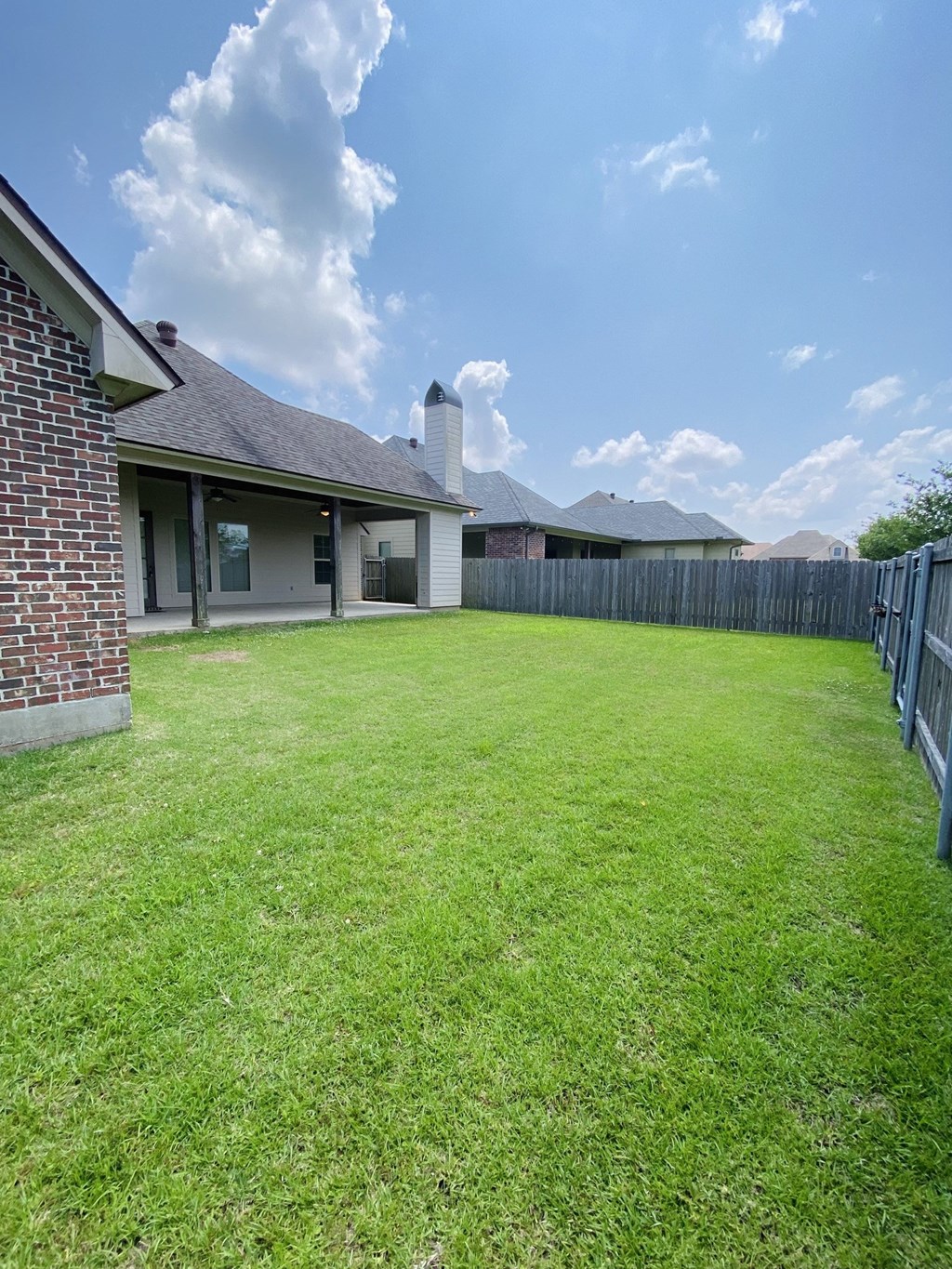 a yard with a fence and a house in the background