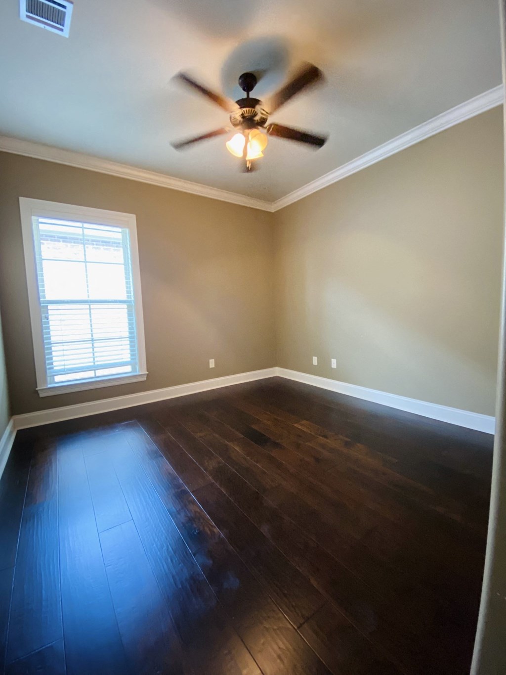a empty room with wooden floors and a ceiling fan