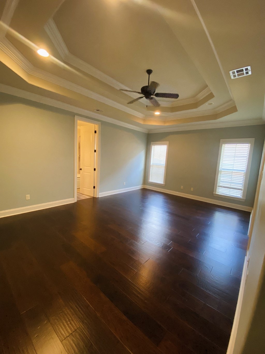 an empty living room with wooden floors and a ceiling fan