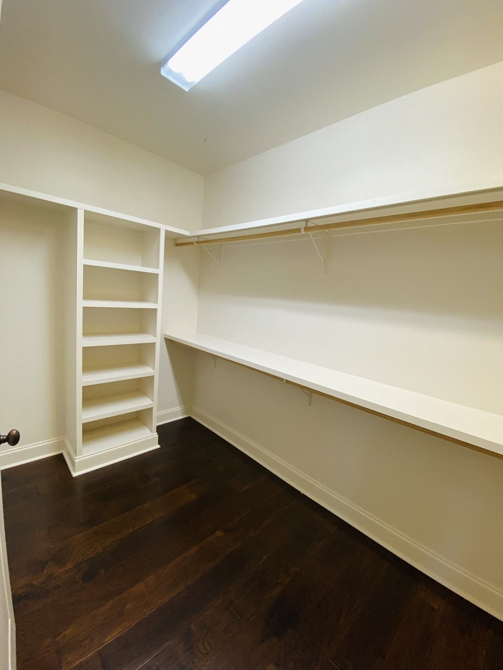 a walk in closet with shelves and a wooden floor
