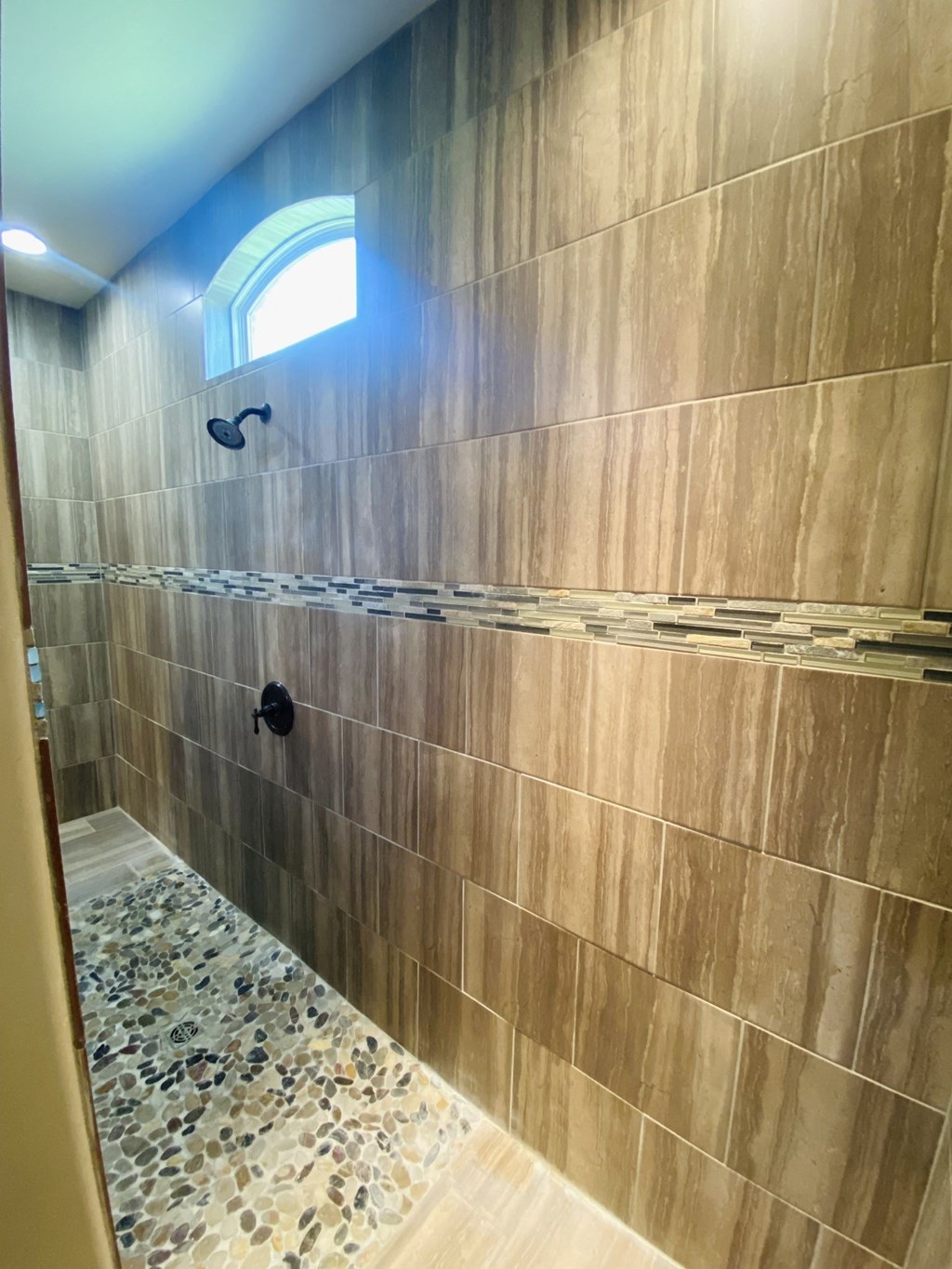 a large tiled shower in a bathroom with a window