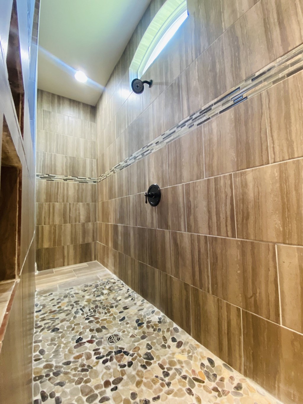 a large shower in a large tile bathroom with a glass door