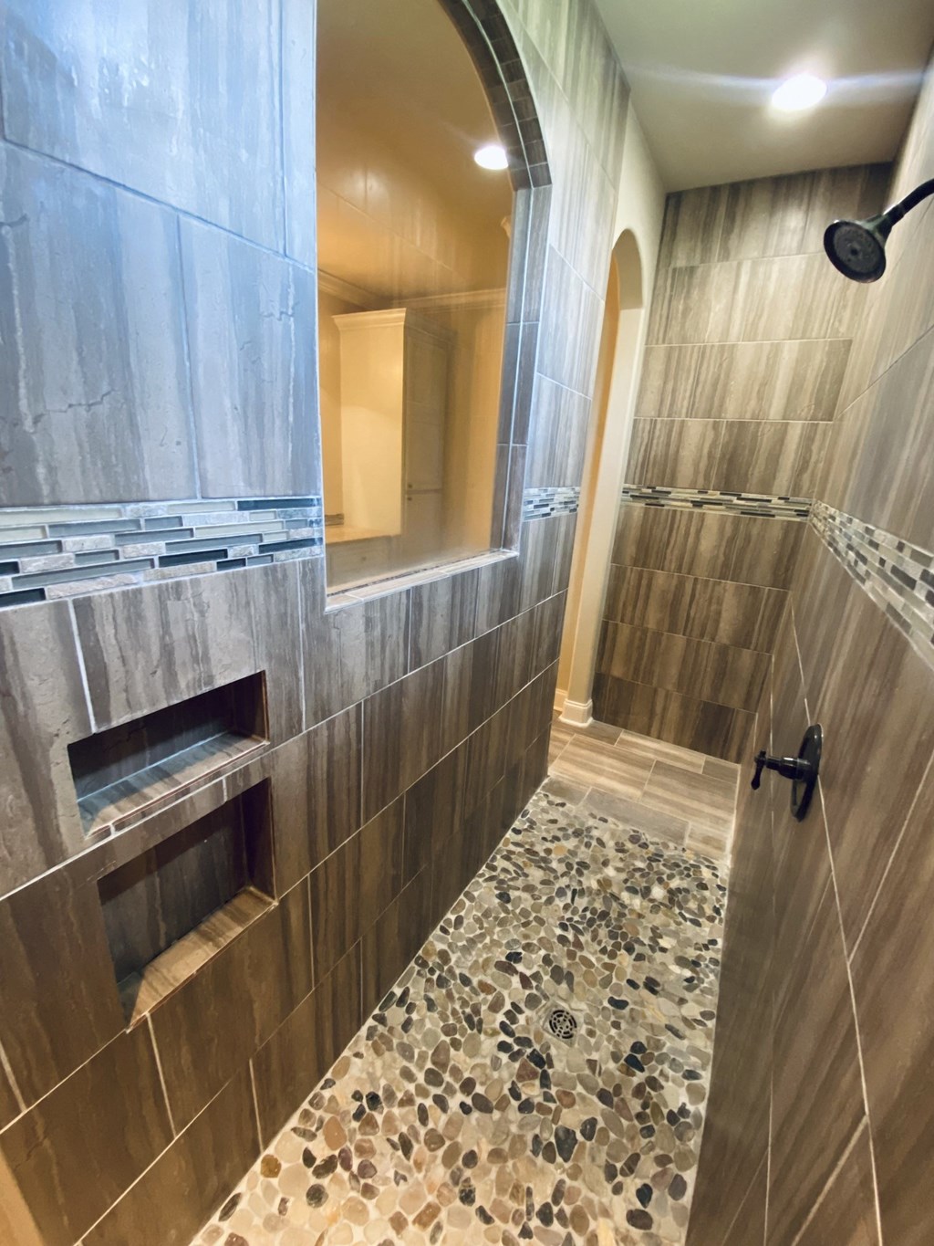 a large shower with a glass door in a tiled bathroom