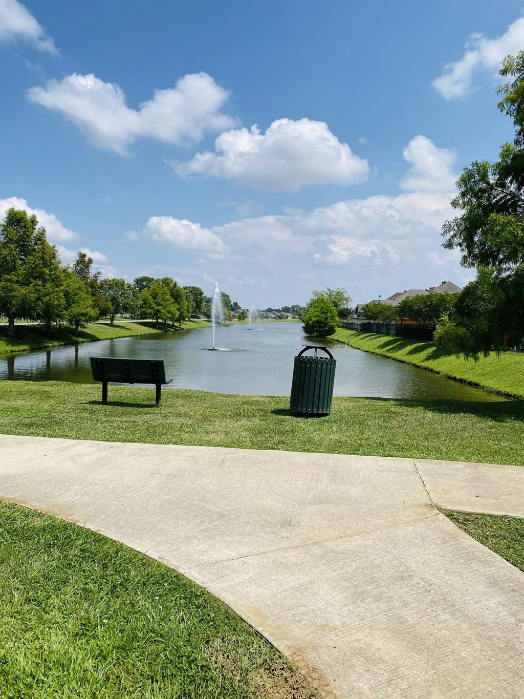 a park with a bench and a pond with a fountain